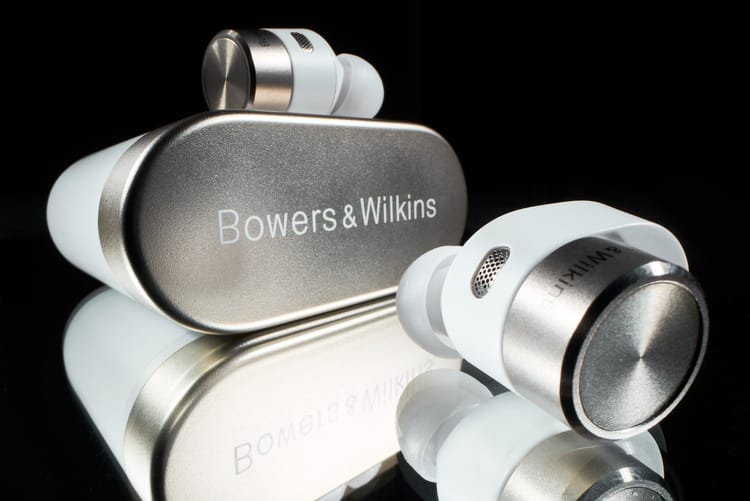Kabellose Earbuds mit silbernem Ladeetui spiegeln sich auf schwarzem Untergrund