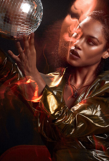 Frau in goldener Metallic-Jacke mit Discokugel im roten Licht