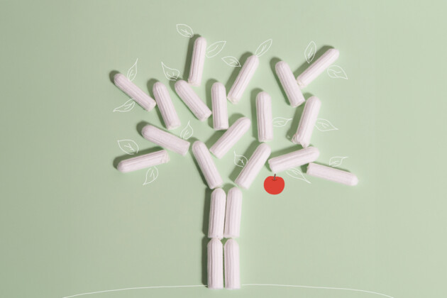 Tampons als Baum mit rotem Apfel auf grünem Hintergrund, Produktfotografie