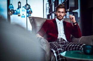 Mann im roten Samtsakko sitzt auf einem Sofa, Lifestyle-Porträt
