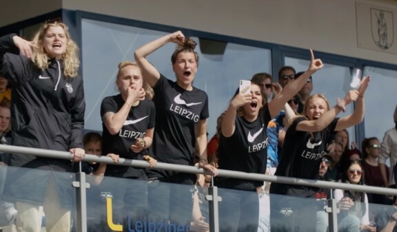 Fans und Spielerinnen jubeln auf einer Tribüne